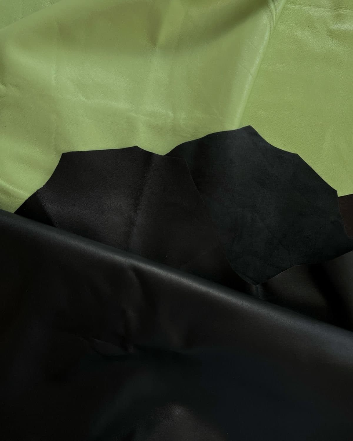 Black leather hides arranged on a cutting surface.