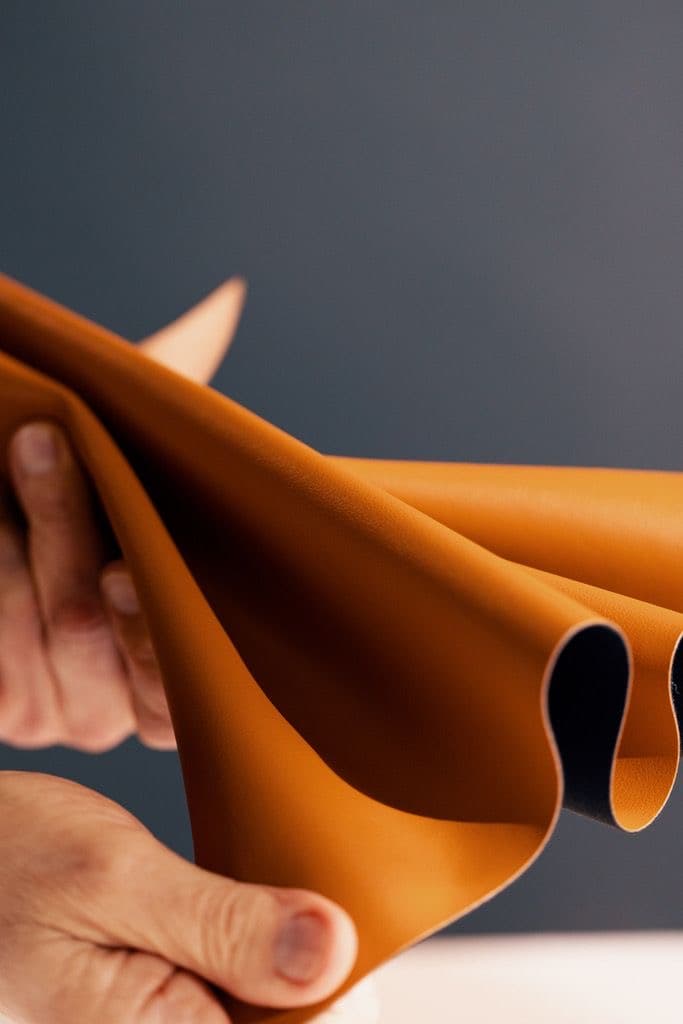 Hand lifting a caramel leather fold.